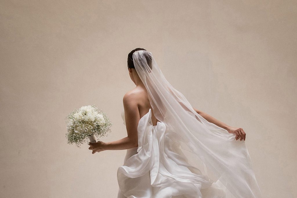 Una foto artistica di una sposa di spalle mentre si tiene il velo realizzata da Antonino Gitto