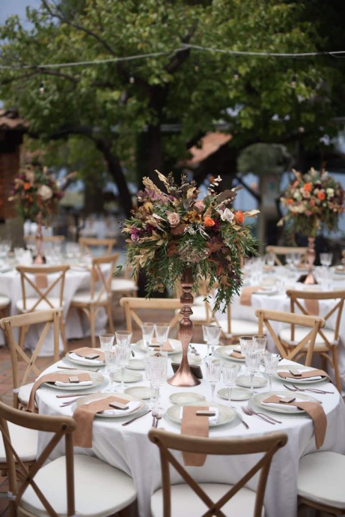 In questa foto un tavolo di nozze di forma rotonda allestito da Angela De Patto con fiori di colore bordeaux e caffé