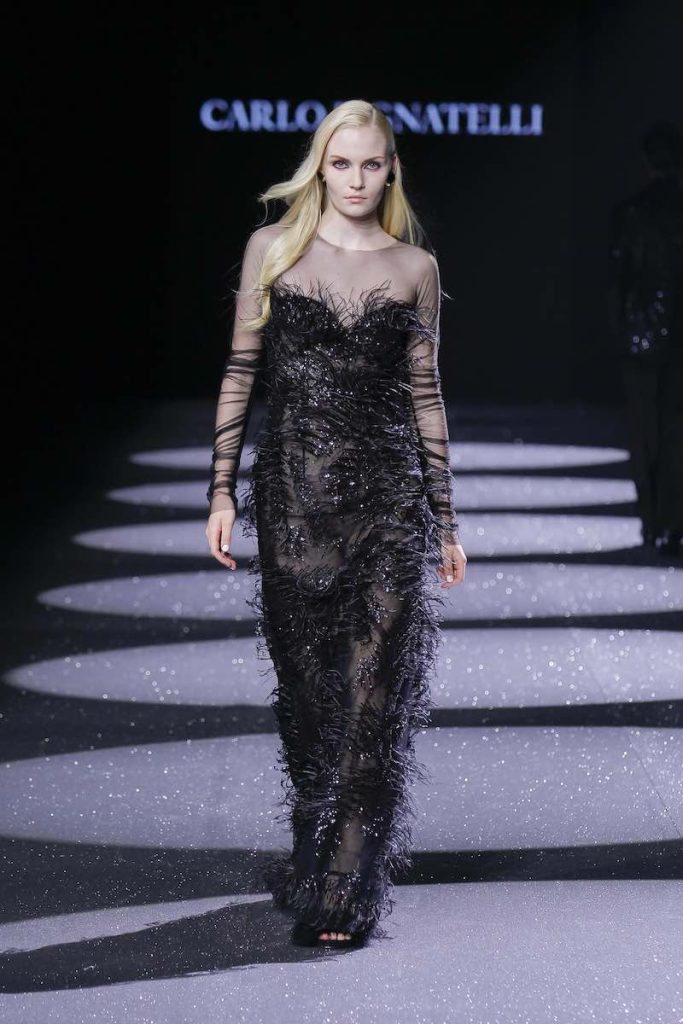 In questa foto una modella sfila indossando un abito Carlo Pignatelli 2024 total black con plumage e trasparenze