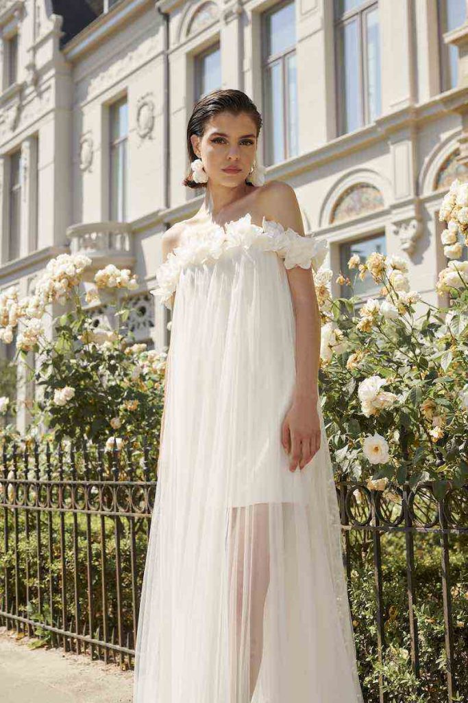 In questa foto una modella posa indossando uno degli abiti da sposa particolari 2024 corto di Marylise con cappa tono su tono