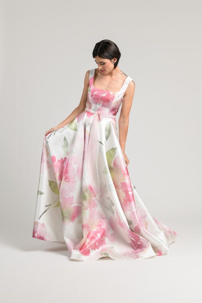 In questa foto una modella posa indossando uno degli abiti da sposa particolari 2024 di Atelier Benedetta in tessuto stampato a fiori di colore rosa