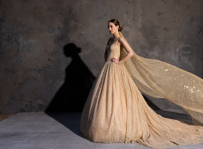 In questa foto una modella posa indossando uno degli abiti da sposa particolari 2024 di Cymbeline di colore oro