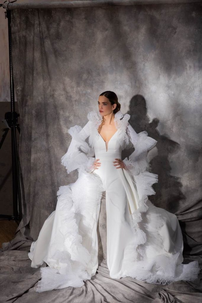 In questa foto una modella posa indossando un abito da sposa con balze a motivi astratti di Cymbeline