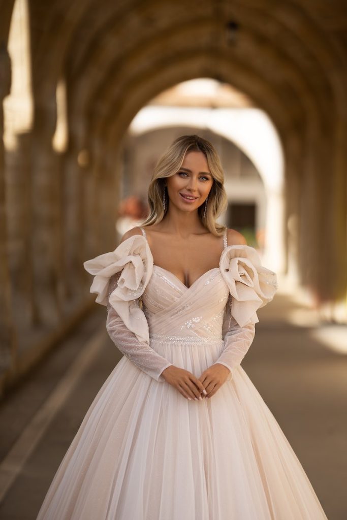 In questa foto una modella posa indossando uno degli abiti da sposa particolari 2024 con rose over e di colore rosa di Daniela Di Marino