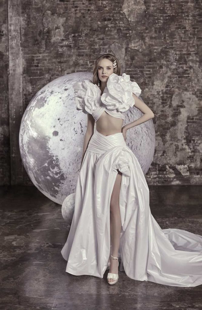 In questa foto una modella posa indossando uno degli abiti da sposa particolari 2024 con crop top di Elisabetta Polignano con maxi ruches sulle spalle