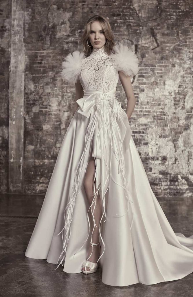 In questa foto una modella posa indossando un abito da sposa ampio con alternanza di stoffe diverse di Elisabetta Polignano