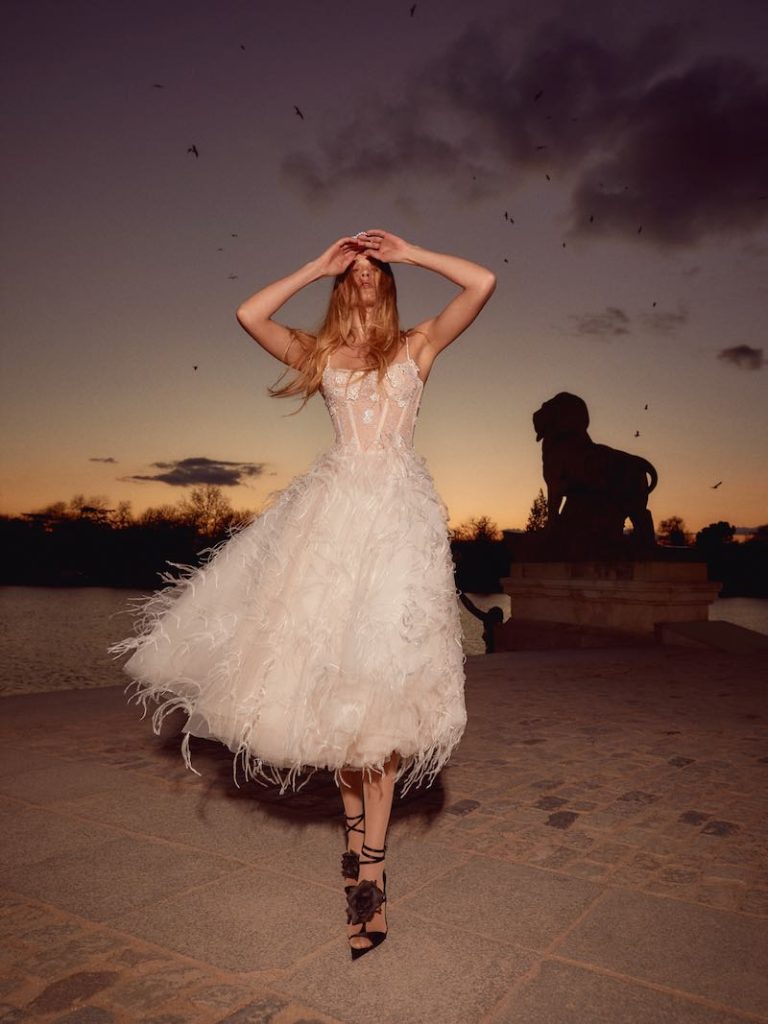 In questa foto una modella posa indossando un abito da sposa midi a campana con plumage di Galia Lahav