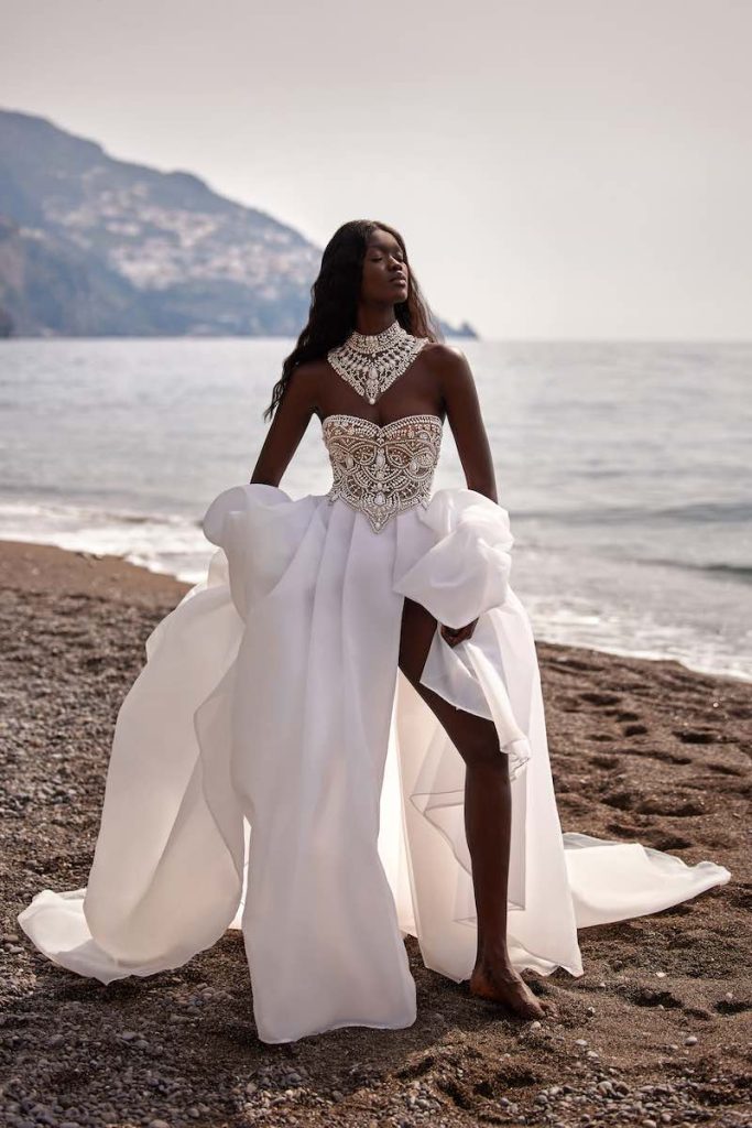 In questa foto una modella posa indossando uno degli abiti da sposa particolari 2024 modello ampio con dettagli gioiello sul corpetto di Julie Vino