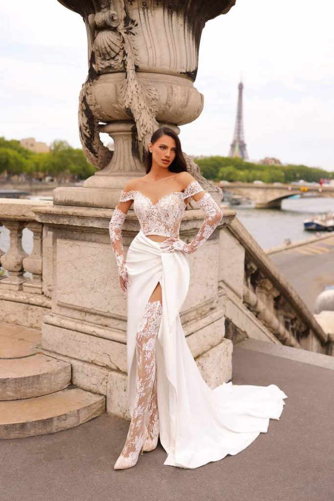 In questa foto una modella posa indossando uno degli abiti da sposa particolari 2024 con crop top a maniche lunghe in pizzo di Michela Ferriero