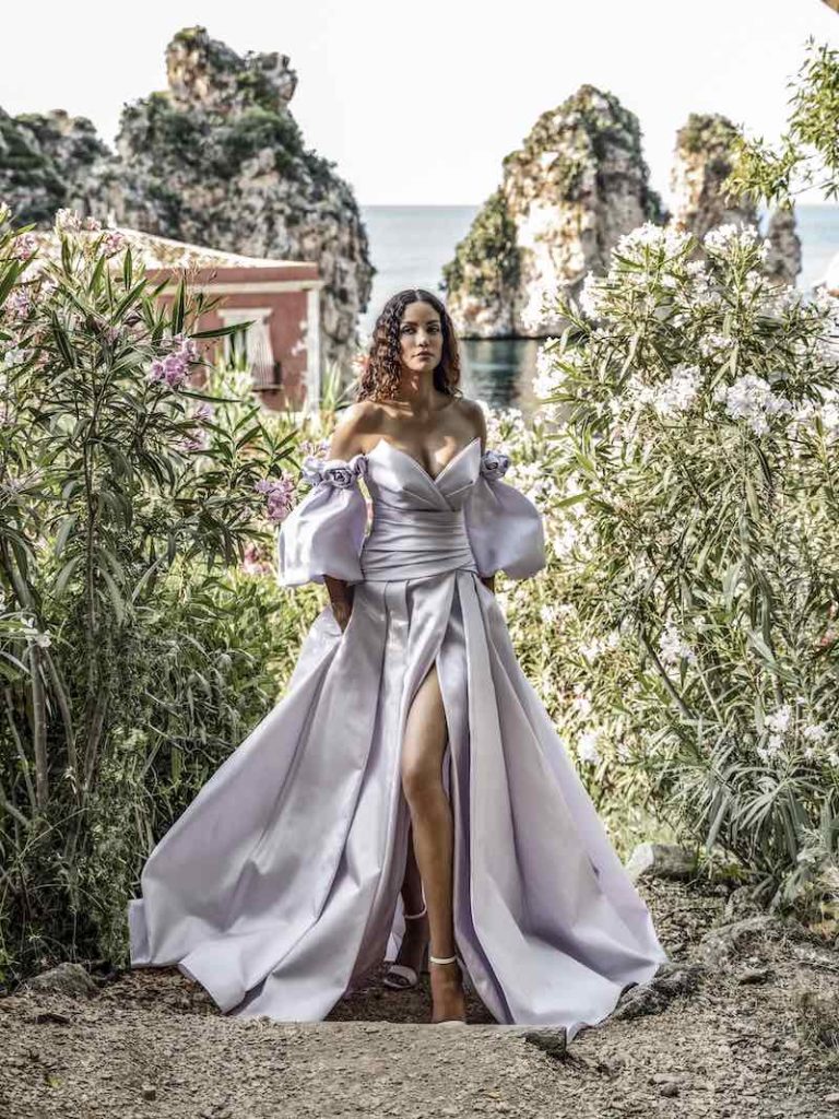In questa foto una modella posa indossando uno degli abiti da sposa particolari 2024 di Alessandro Angelozzi in mikado di colore lilla