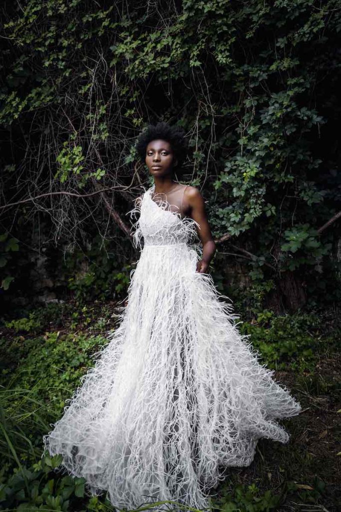 In questa foto una modella posa indossando un abito da sposa ad A con plumage di Andrea Sedici 