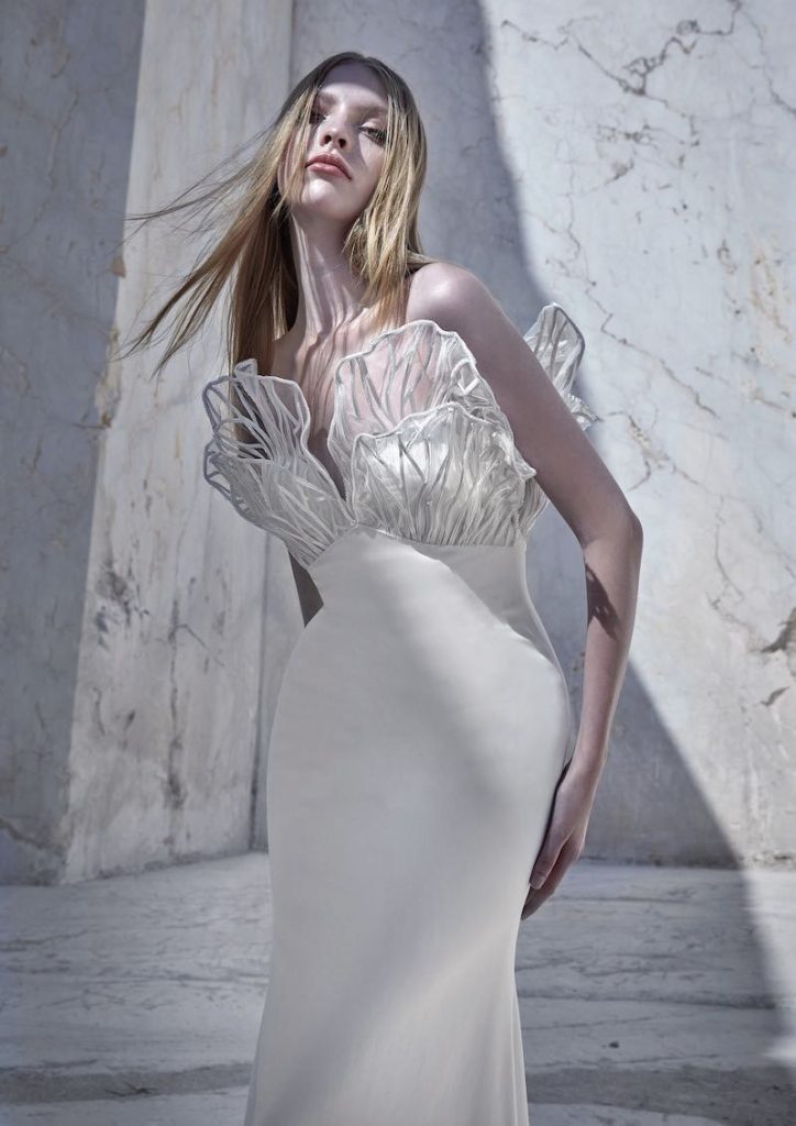 In questa foto una modella posa indossando un abito da sposa a sirena con motivo astratto sul corpetto di Atelier Pronovias