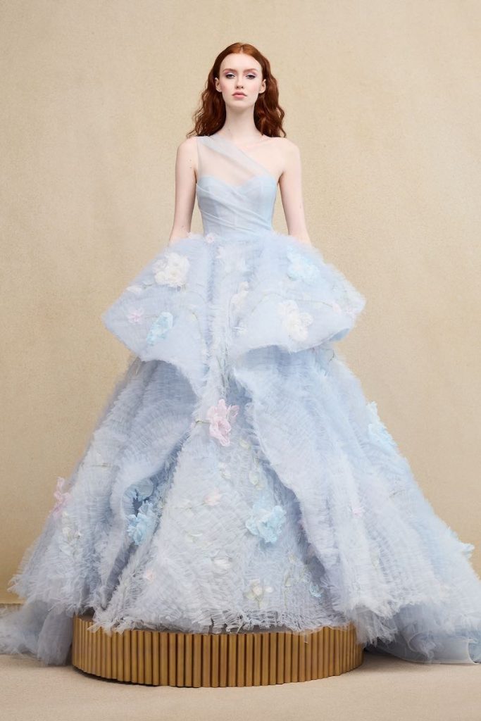 In questa foto una modella posa indossando uno degli abiti da sposa particolari 2024 di Ines Di Santo in tulle di colore azzurro con fiori 3D