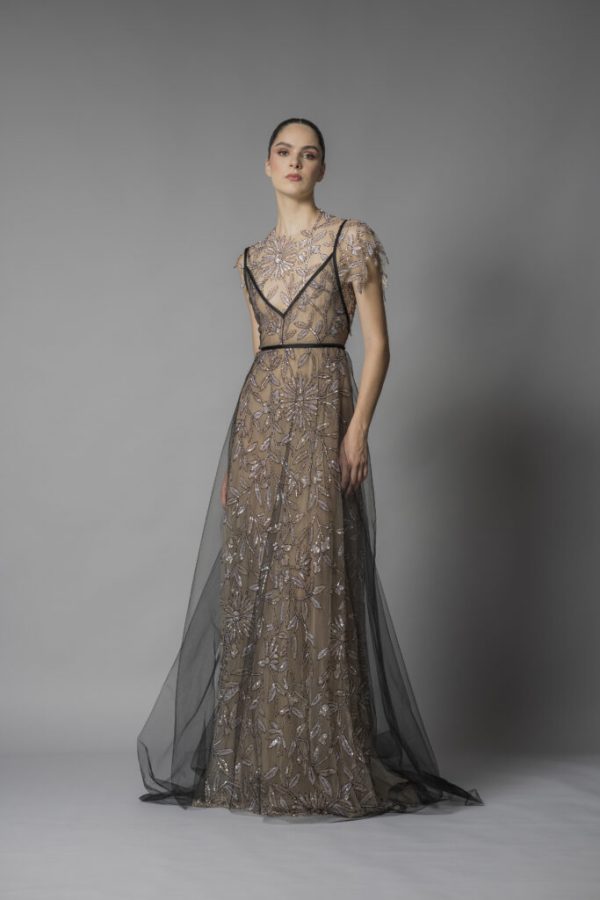 In questa foto una modella posa indossando uno degli abiti da sposa particolari 2024 modello scivolato di Marco y Maria con ricami di perline e uno strato di tulle di colore nero