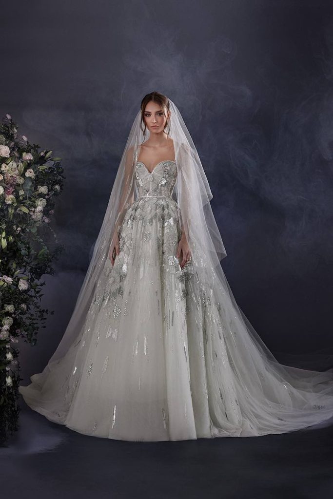 In questa foto una modella posa indossando uno degli abiti da sposa particolari 2024 di Zuhair Murad con ricami di paillettes e perline di colore argento