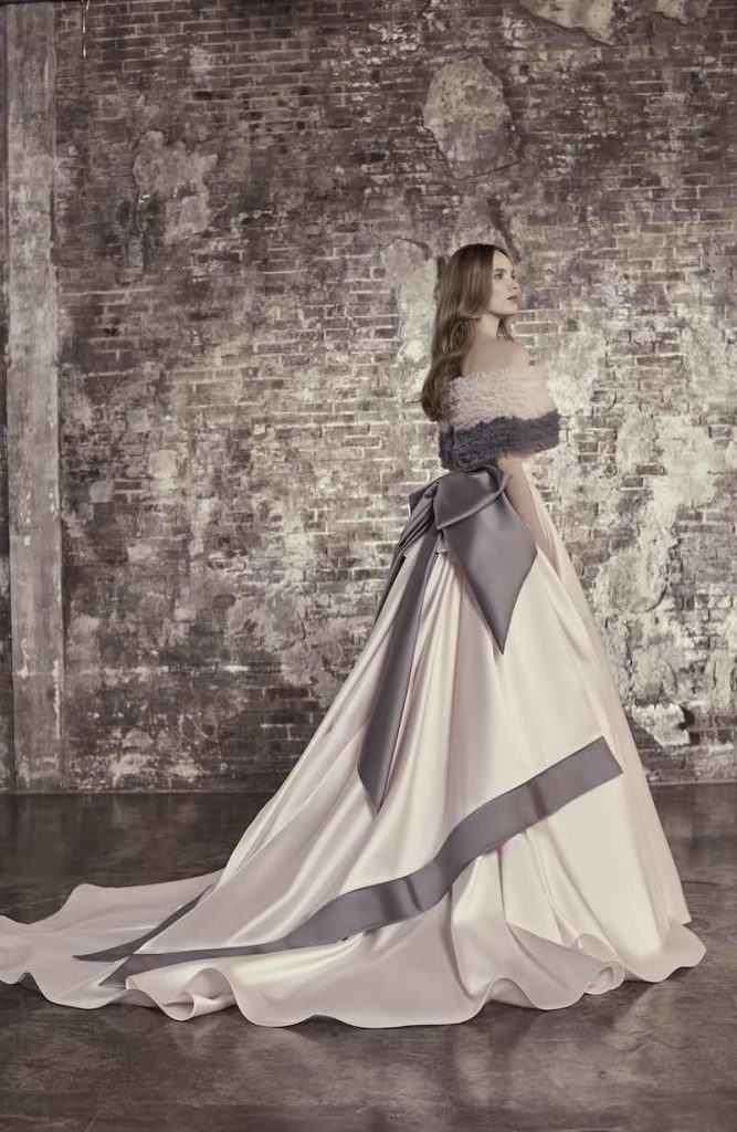 In questa foto una modella posa indossando un abito da sposa ampio con alternanza di stoffe diverse di Elisabetta Polignano