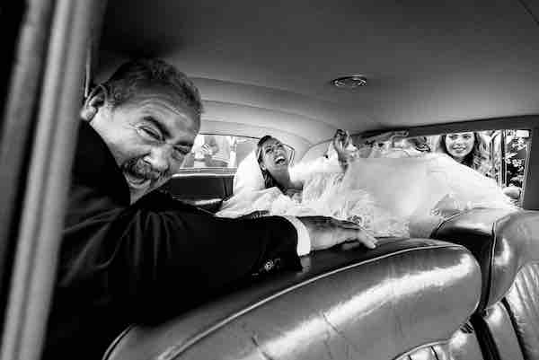 In questa foto in bianco e nero di Pierpaolo Perri una sposa e il papà ridono dentro all'auto del matrimonio