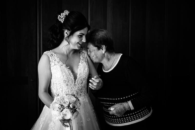In questa foto in bianco e nero di Pierpaolo Perri una nonna bacia il braccio della nipote in abito da sposa