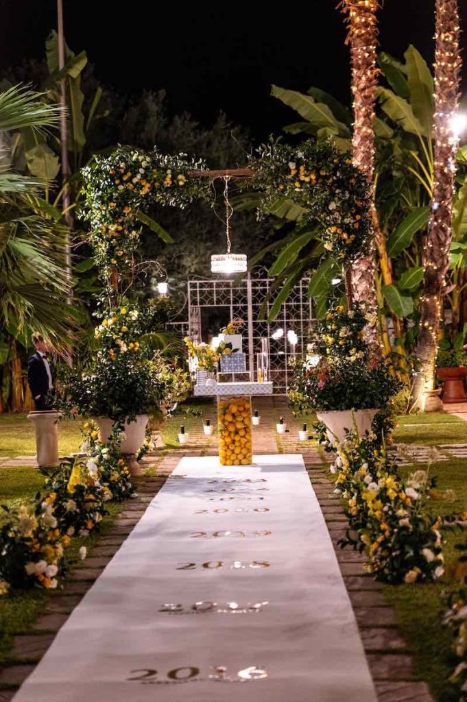 In questa foto l'angolo per il taglio della torta nuziale decorato dalla Wedding Designer Angela De Patto con limoni, rampicanti e fiori di colore giallo
