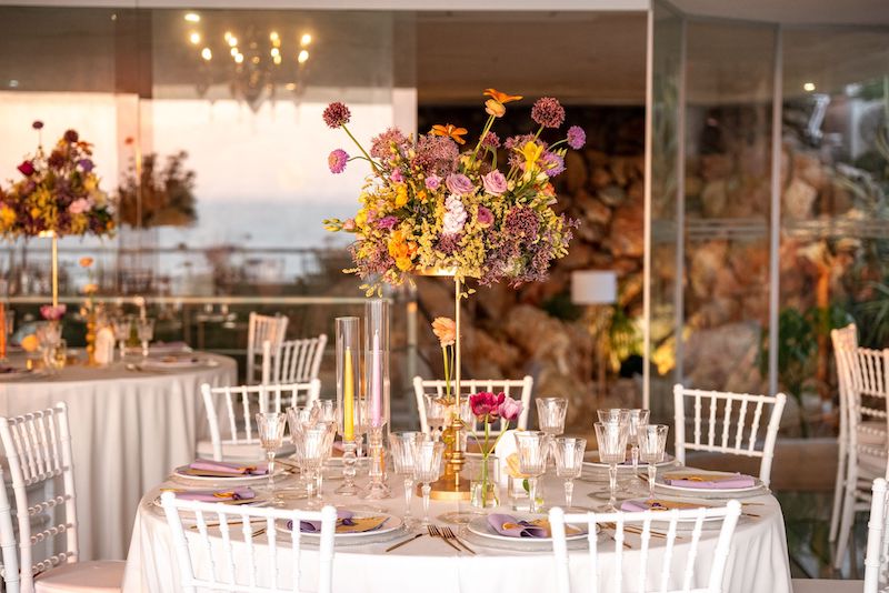 In questa foto un tavolo di nozze di forma rotonda allestito da Angela De Patto con fiori di colore giallo e lilla 