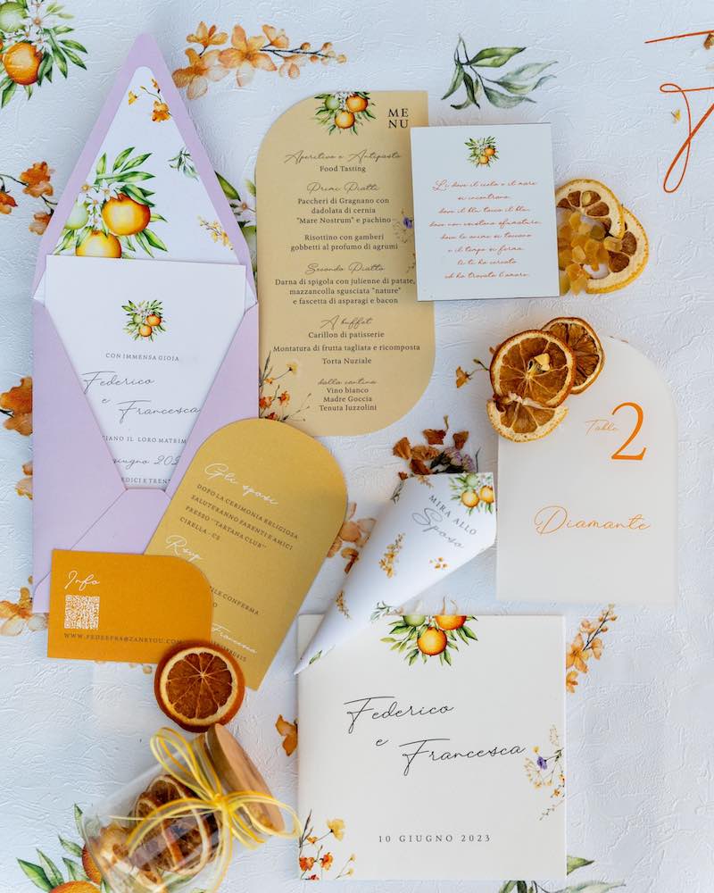In questa foto un coordinato grafico di matrimonio nei toni del giallo, dell'arancione e del lilla progettato da Angela De Patto