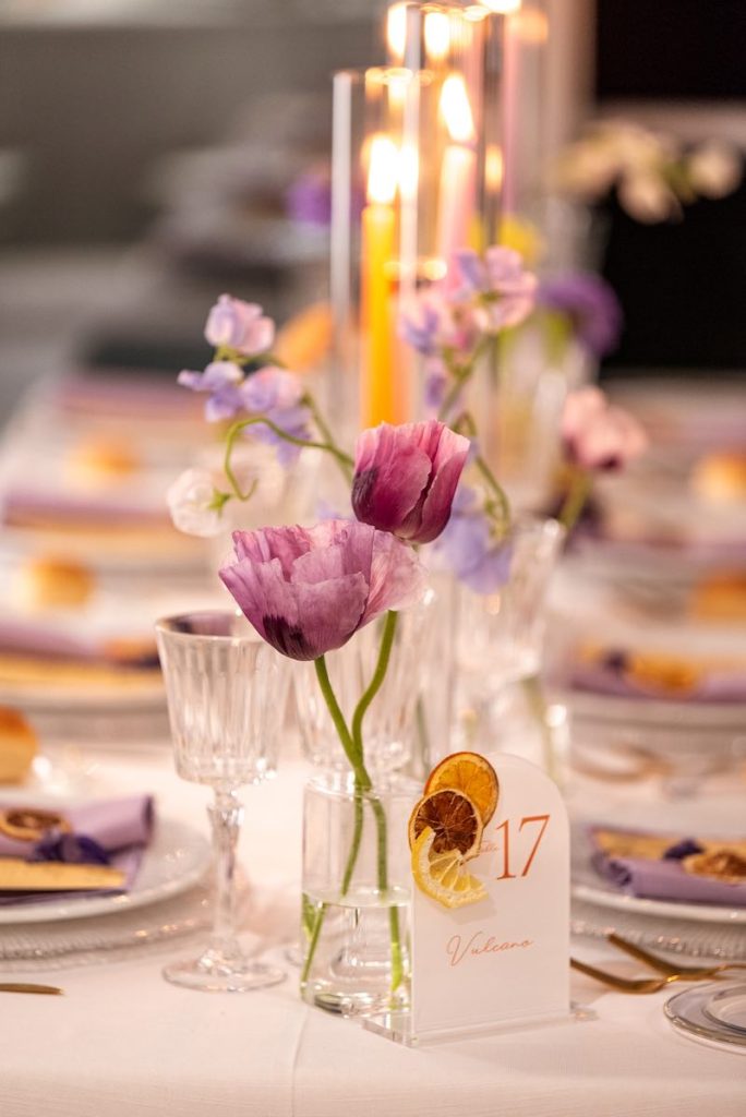 In questa foto il dettaglio della decorazione di un tavolo di nozze decorato con fiori di colore lilla e frutta essiccata di colore giallo 