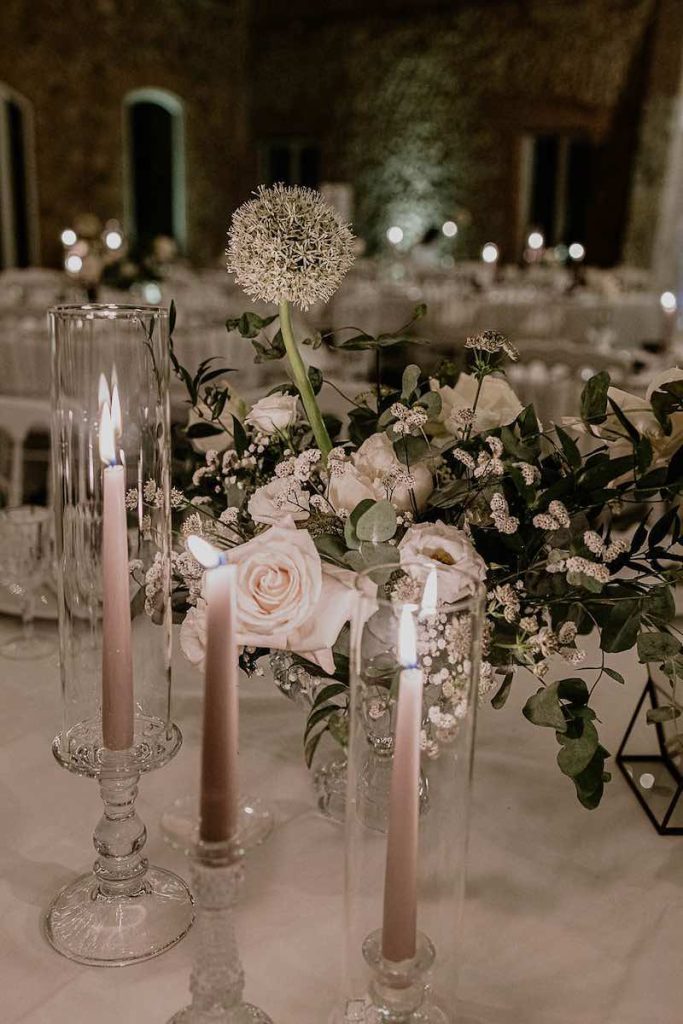 In questa foto un dettaglio della mise en place del matrimonio di Lucio e Federica realizzata dalla Wedding Planner Antonella Candido con candele di colore bianco, portacandele in vetro e fiori di colore bianco