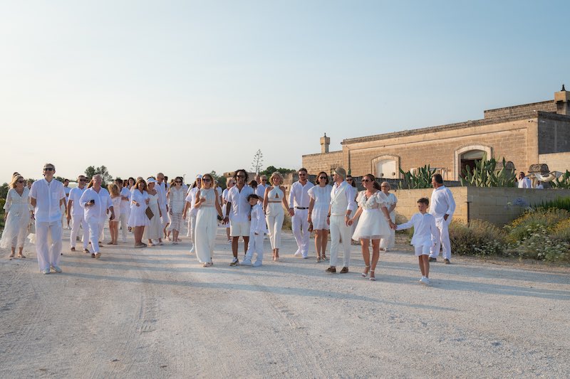 In questa foto gli sposi e i loro invitati vestiti di colore in bianco festeggiano il Wine Wedding a Masseria Cuturi 