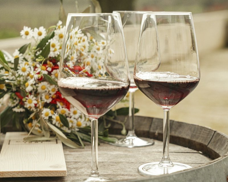 In questa foto due calici di vino rosso poggiati su una botte