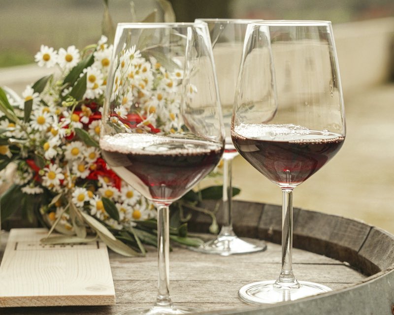 In questa foto due calici di vino rosso poggiati su una botte