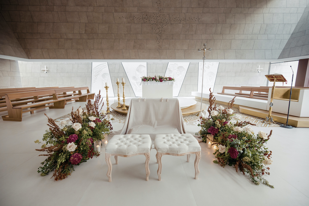 In questa foto l'altare di una chiesa per matrimonio allestito nei toni del bordeaux e del bianco