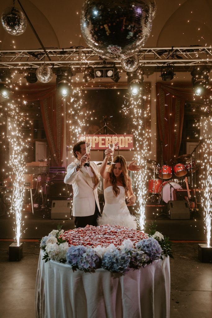 In questa foto una coppia di sposi durante il taglio della torta, alla fine del loro matrimonio organizzato da Corsini.Events Group