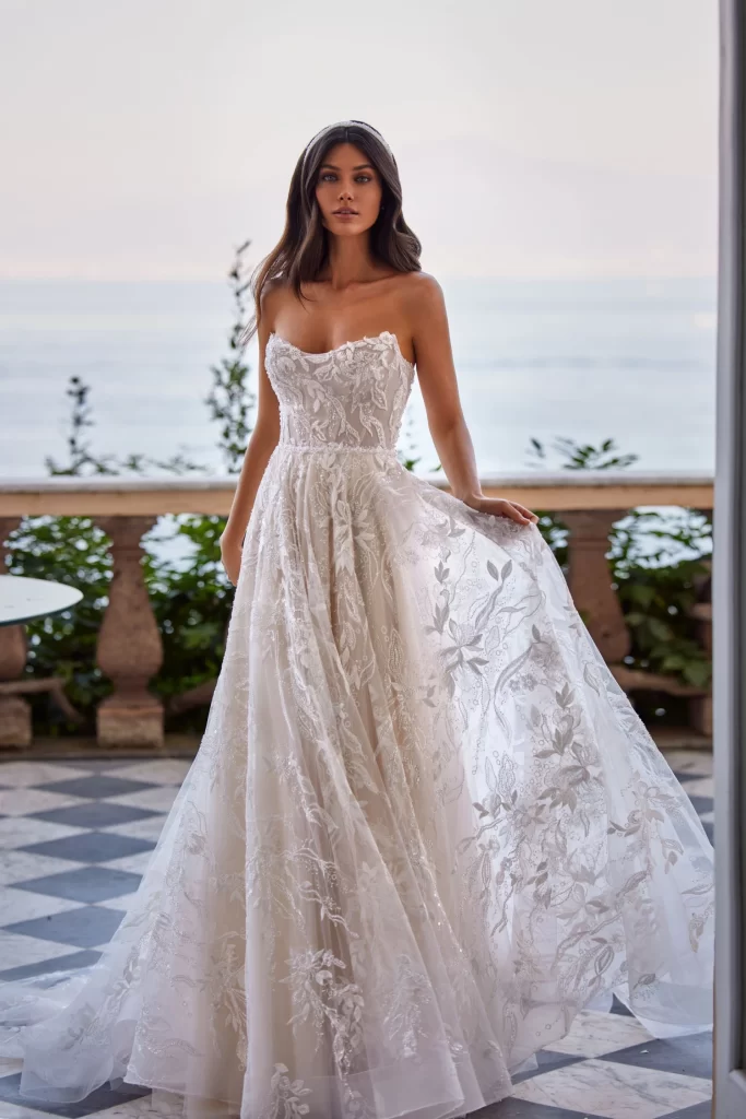 In questa foto la modella indossa un abito da sposa con dettagli floreali Pollardi 2024.