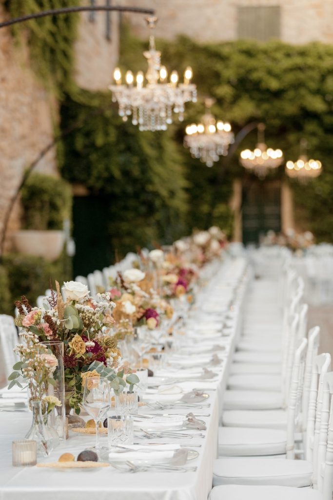 In questa foto un tavolo imperiale allestito con coppe di fiori di colore bordeaux e rose Playa e rose cappuccino