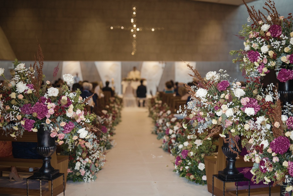 In questa foto l'allestimento di una chiesa per un matrimonio nei toni del bordeaux e del bianco