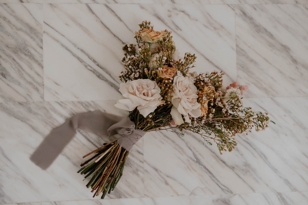 In questa foto un bouquet a stelo lungo con rose e chamelaucium legati da un nastro di chiffon di colore grigio