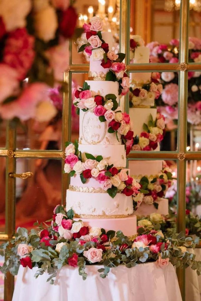 In questa foto una torta nuziale a piani decorata con fiori di colore rosa, bianco e fucsia
