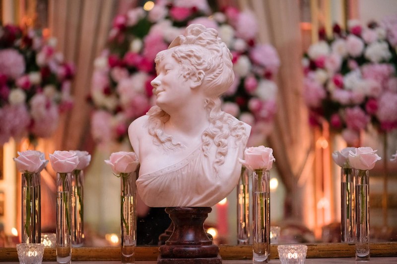 In questa foto un dettaglio di un allestimento progettato da Barbara Vissani composto da portafiori singoli con rose di colore rosa, un mezzobusto di marmo e fiori nei toni del rosa e del fucsia