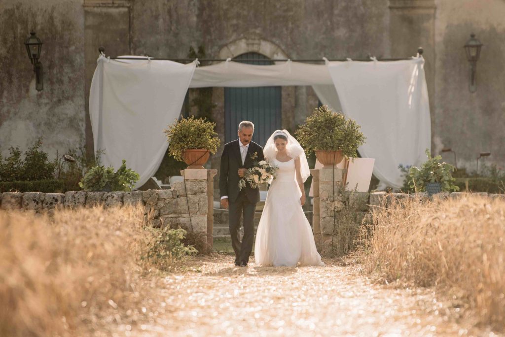 In questa immagine la sposa al braccio del padre mentre fa il suo ingresso. 