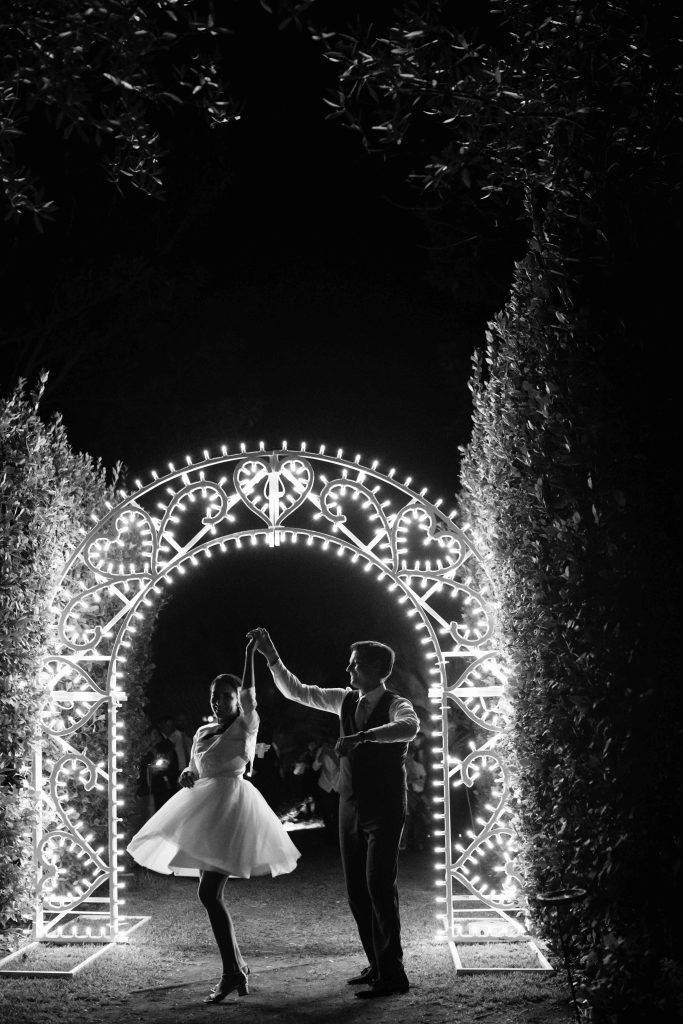 In questa immagine gli sposi ballano e sullo sfondo le luminarie con cuori. 
