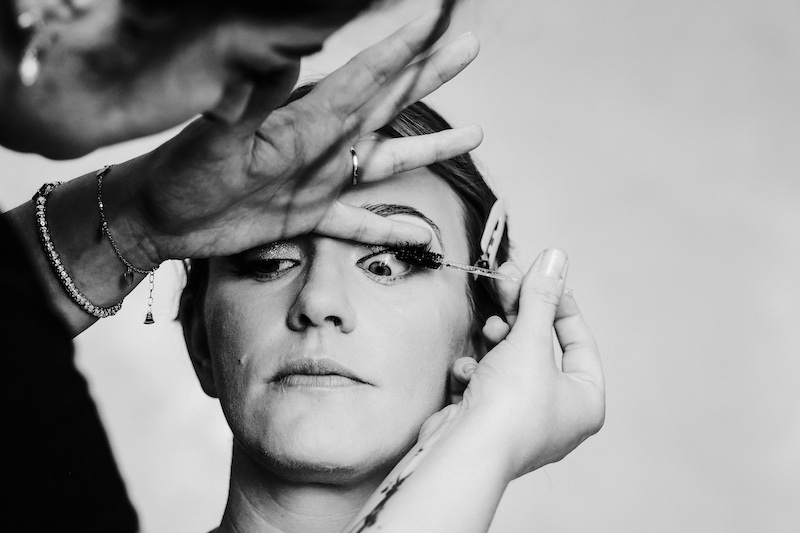 In questa foto in bianco e nero di Fabio Betelli una sposa mentre viene truccata dalla make-up artist che le mette del mascara sulle ciglia