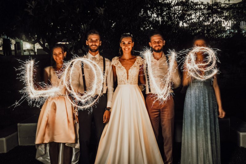 In questa foto di Fabio Betelli due sposi con i loro testimoni scrivono la parola "Love" con la tecnica del Light Painting