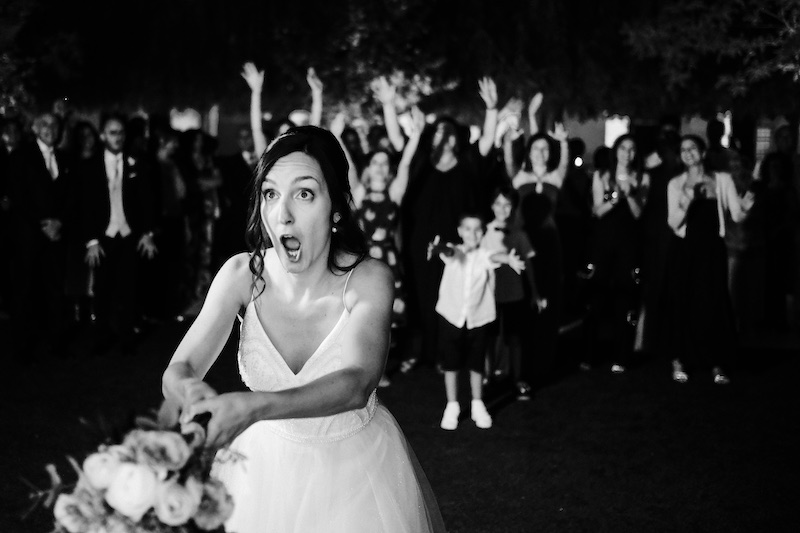 In questa foto in bianco e nero una sposa mentre lancia il suo bouquet di nozze