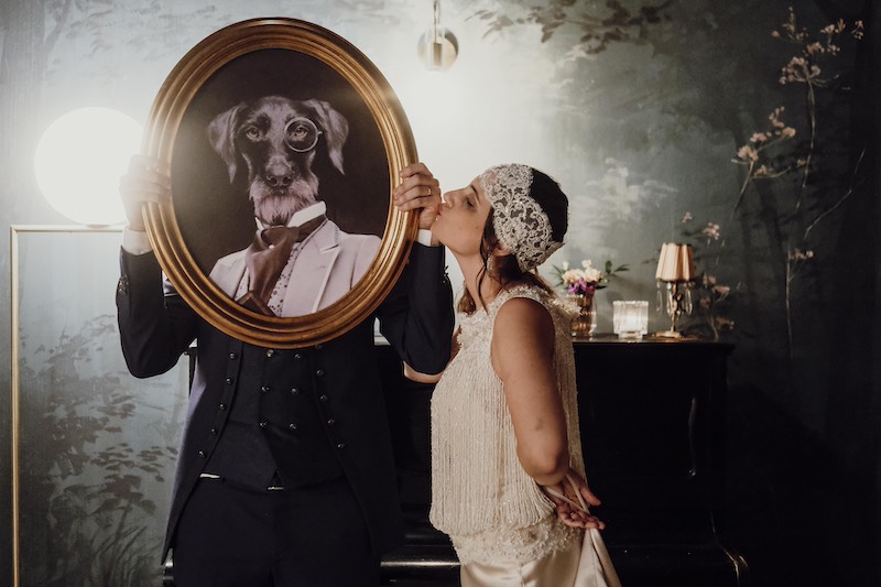 In questa foto divertente di Fabio Betelli una sposa con un abito stile anni '20 mentre finge di baciare il ritratto di un cane vestito con abiti eleganti