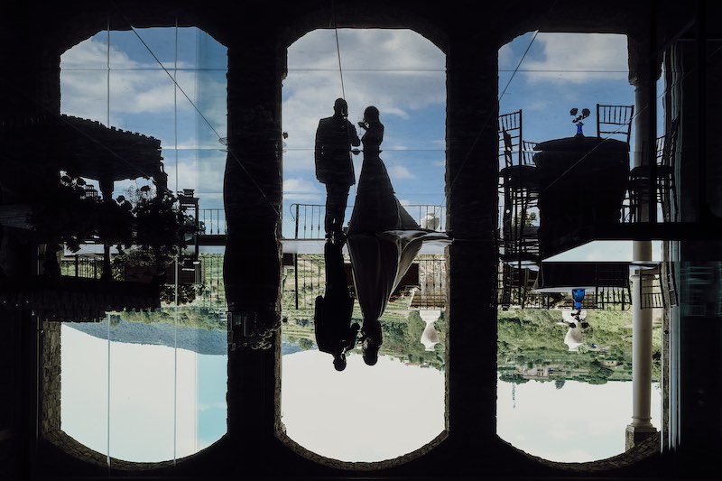 In questa foto del fotografo di matrimonio Fabio Betelli due sposi in ombra durante il loro ricevimento di nozze mentre riflettono la loro immagine sulla superficie di una piscina