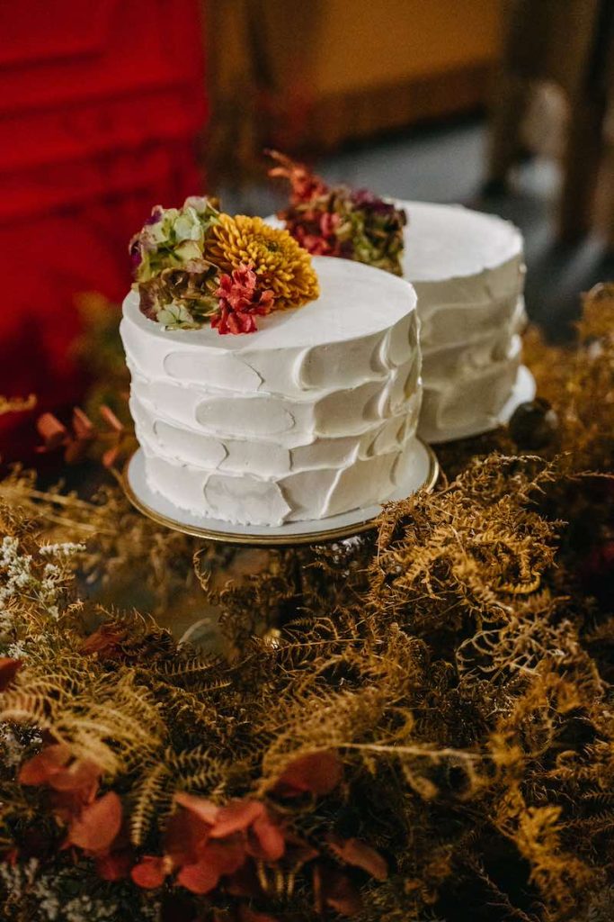 In questa foto due torte per matrimonio decorata con pennellate di ghiaccia di colore bianco e fiori secchi