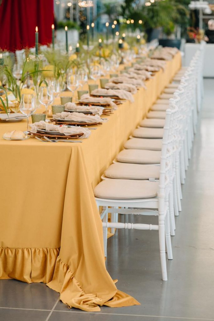 In questa foto un tavolo imperiale decorato da NoidueWedding per un matrimonio con fiori secchi di colore verde, cedri, candele di colore verde e tovagliato color giallo