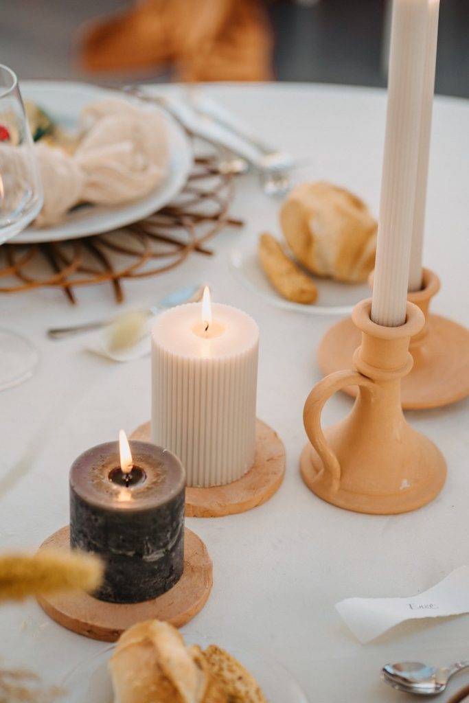 In questa foto un dettaglio di mise en place di nozze sviluppata da NoidueWedding con candele di colore grigio antracite e bianco e candelabri di terracotta
