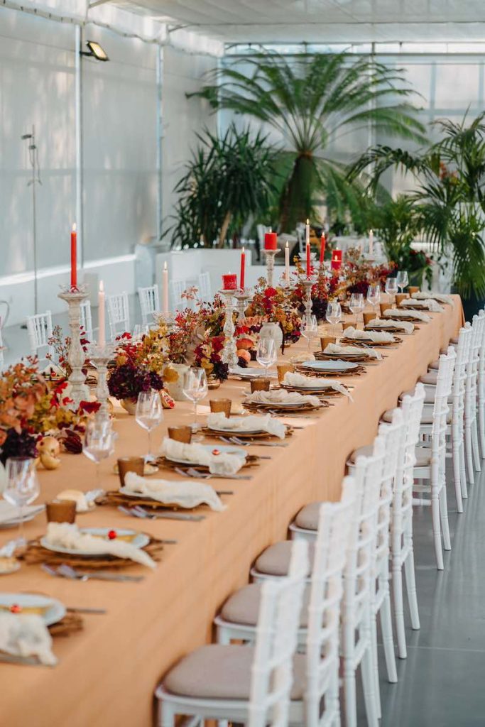 In questa foto un tavolo imperiale decorato da NoidueWedding per un matrimonio con fiori secchi di colore rosso, melograni, candele di colore rosso e bianco e tovagliato color ruggine