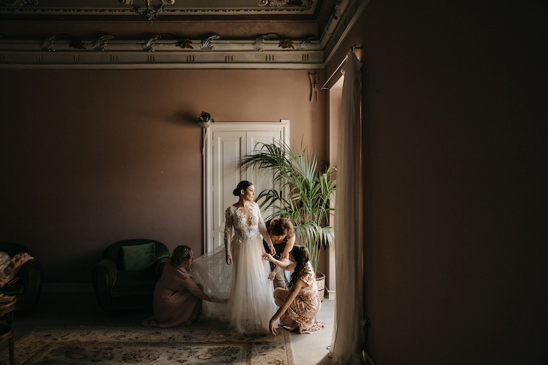 In questa foto una sposa si prepara insieme alle sue damigelle di nozze all'interno di una stanza in un palazzo nobiliare